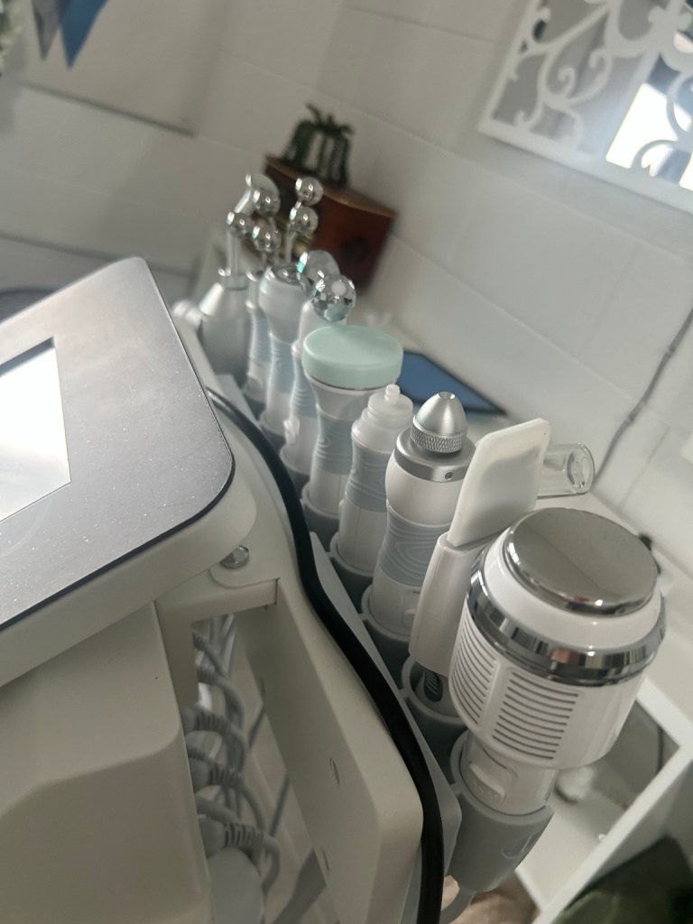 Close-up of various aesthetic machine attachments with silver and plastic heads on a clinic trolley