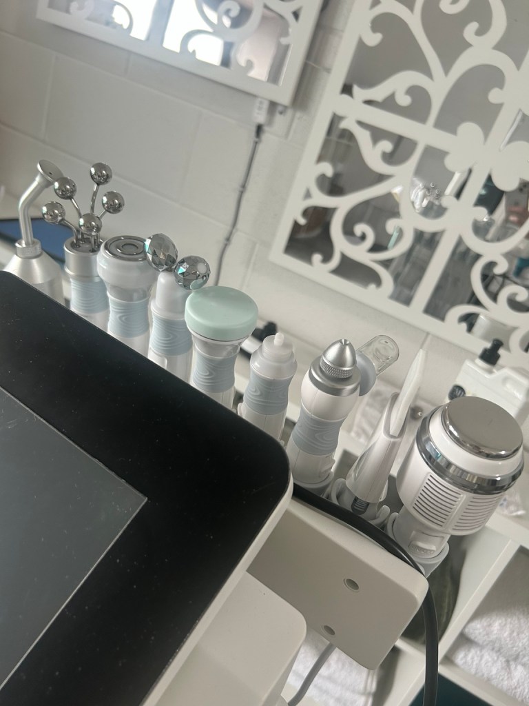 Close-up of various aesthetic machine attachments with silver and plastic heads on a clinic trolley.